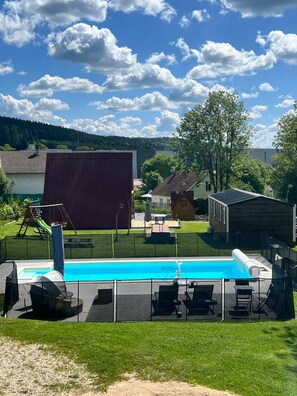 Quintal com piscina, deck de madeira e  área cercada.