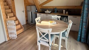 En inredning med träpanel, ett matbord, stolar, ett köksutrymme och en trappa.
