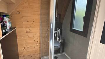 Een douchekamer met glazen wanden, een houten plafond en een raam.
