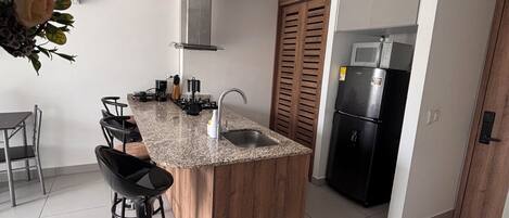 A modern kitchen with a central island, stainless steel appliances, and a dining area with bar stools.