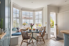 A bay window seating area with a table, chairs, and a vase of flowers. - Bay View House, Broadstairs (Broadstairs)