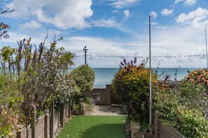 A garden with a brick wall, a lamp post, and a view of the sea. - Bay View House, Broadstairs (Broadstairs)