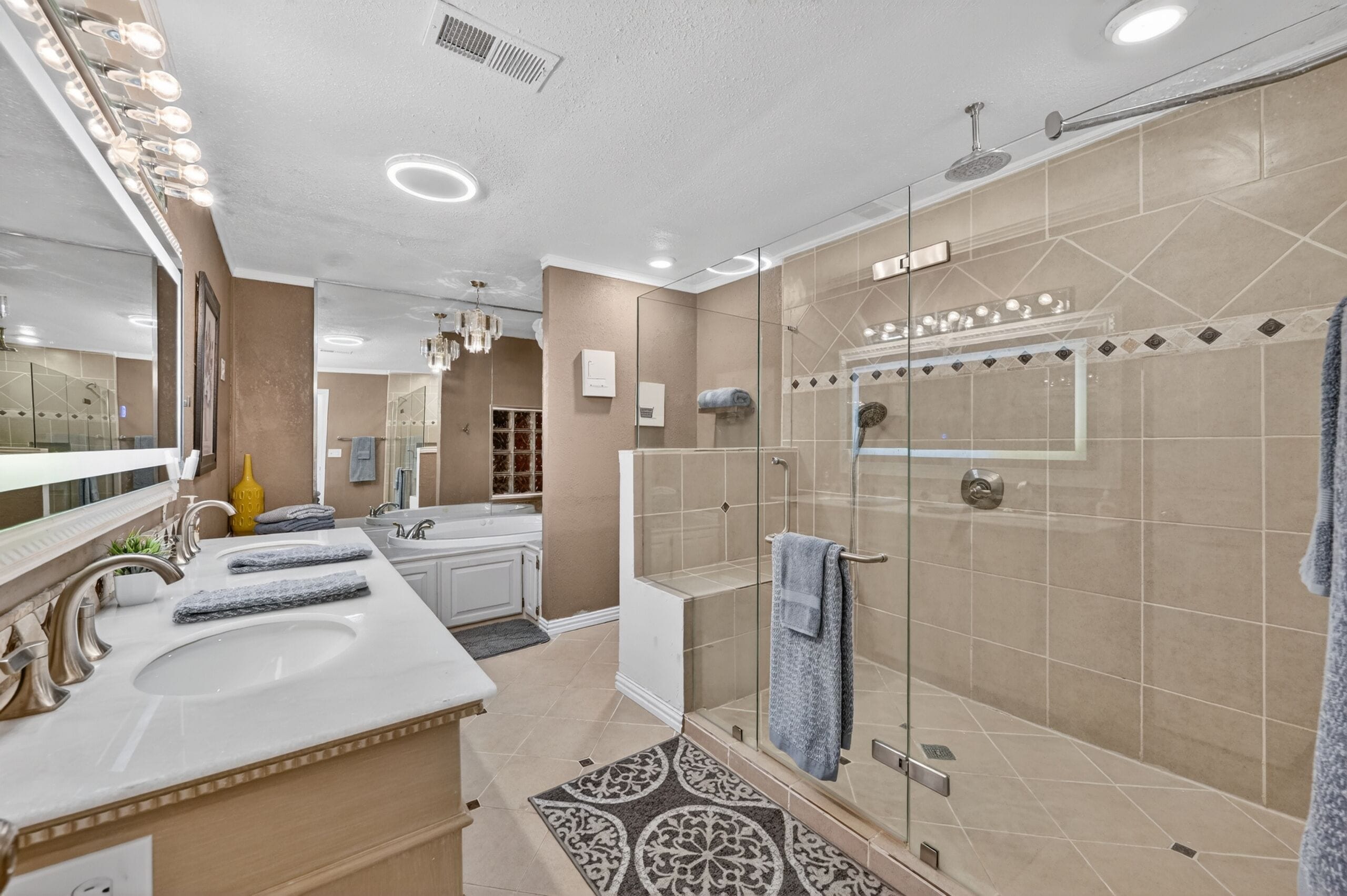 Une salle de bain moderne dotée de deux lavabos, d’une douche à parois de verre et d’un grand miroir.