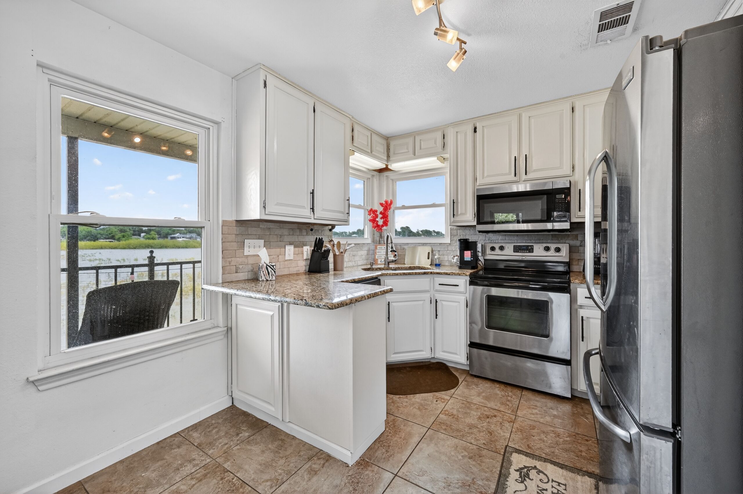 A kitchen with white cabinets, a stainless steel refrigerator, a microwave, and an oven.