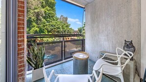 A balcony with a view of trees, a white chair, a table, and a decorative owl statue. - Surry Hills City Studio Near Central Station (Surry Hills)