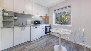 A modern kitchen with white cabinets, a built-in oven, and a window with a view of trees. - Surry Hills City Studio Near Central Station (Surry Hills)