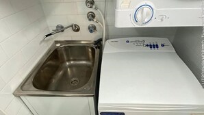 A compact laundry area with a washing machine and a stainless steel sink. - Surry Hills City Studio Near Central Station (Surry Hills)