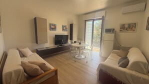 Ein modernes Wohnzimmer mit einer Couch, einem Esstisch und einem Fernseher.