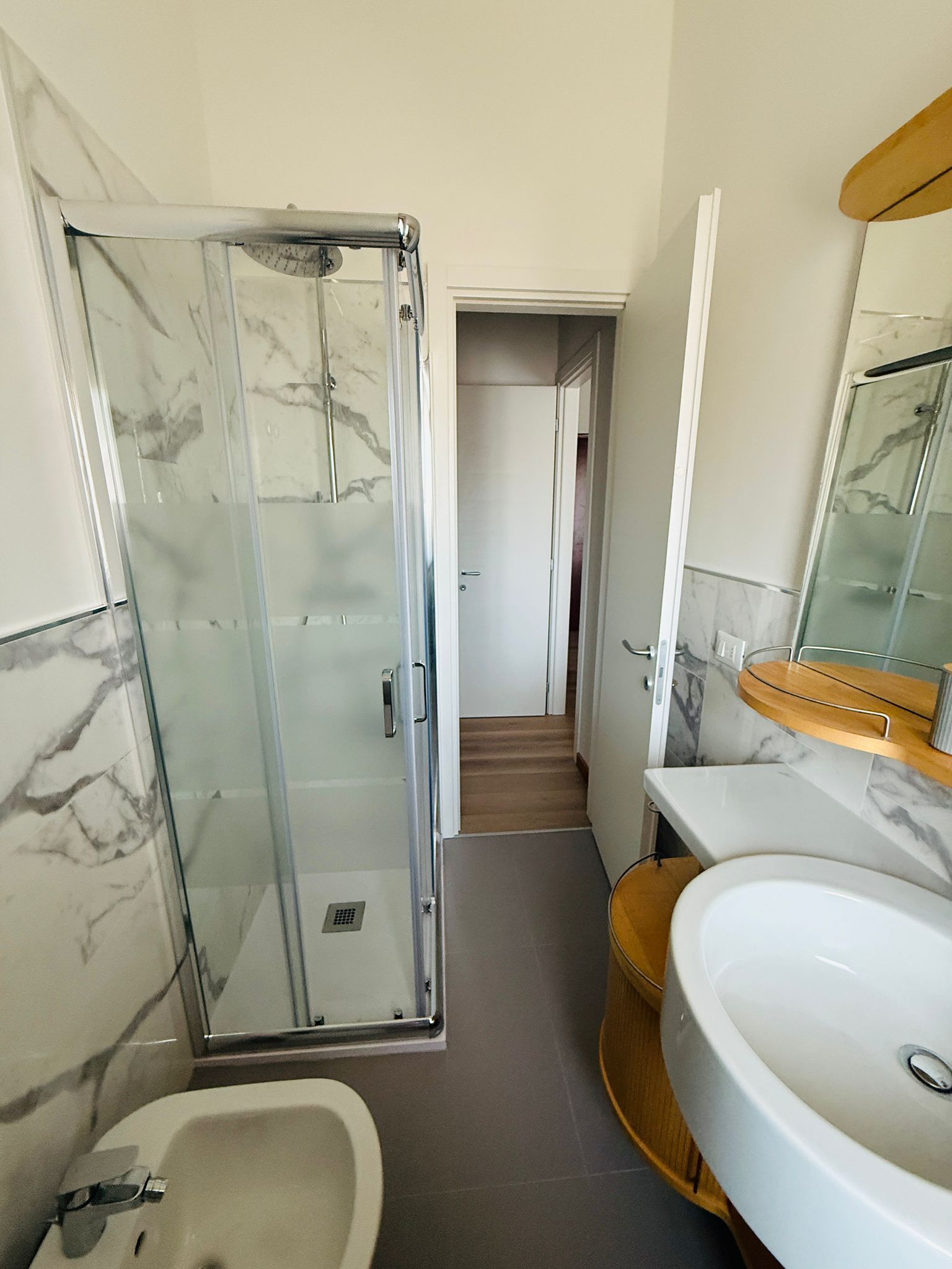 Une salle de bain avec une douche en verre, un lavabo et un miroir.