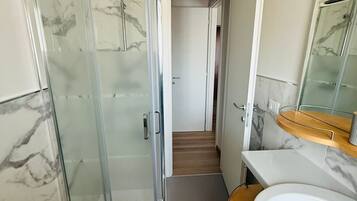 Une salle de bain avec une douche en verre, un lavabo et un miroir.