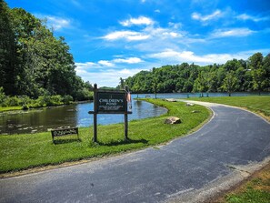A sign for a children's pond with a path leading to it, surrounded by greenery and a body of water. - "Teddy's Rest": Cozy Wooded Cottage in Land Harbor with Lake and Pool Access (Newland)