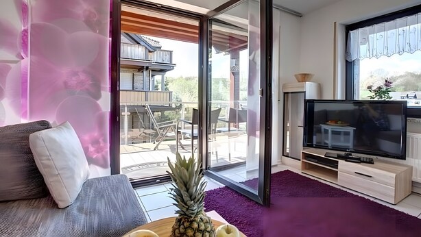 Een moderne woonkamer met een bank, een televisie en een schuifdeur naar een terras.