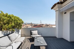 Terraza en la azotea con un sofá, una mesa y vistas a la ciudad.