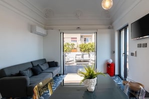 Ein modernes Wohnzimmer mit einer Couch, einem Glastisch und einer Topfpflanze.