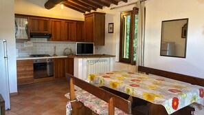 Una cucina con mobili in legno, un fornello, un lavello e un'area pranzo con tavolo e panchetta.