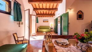 A cozy room with a wooden ceiling, a green sofa, a dining table with wine glasses, and a chair.