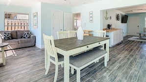 A dining area with a wooden table and chairs, a ceiling fan, and a kitchen area with cabinets and a countertop. -  Waterfront,Private Beach • Dock • Kayaks, Grill ,Firepit,SUN,HeatedPool,3 Beds (Hernando Beach)