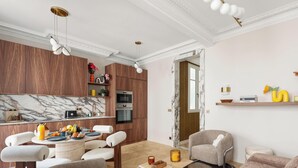 Eine moderne Küche mit Marmor-Spritzschutz, Holzschränken und einem Essbereich mit Tisch und Stühlen.