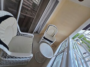 En balkon med en hvid stol, et lille rundt bord og en hvid sofa.