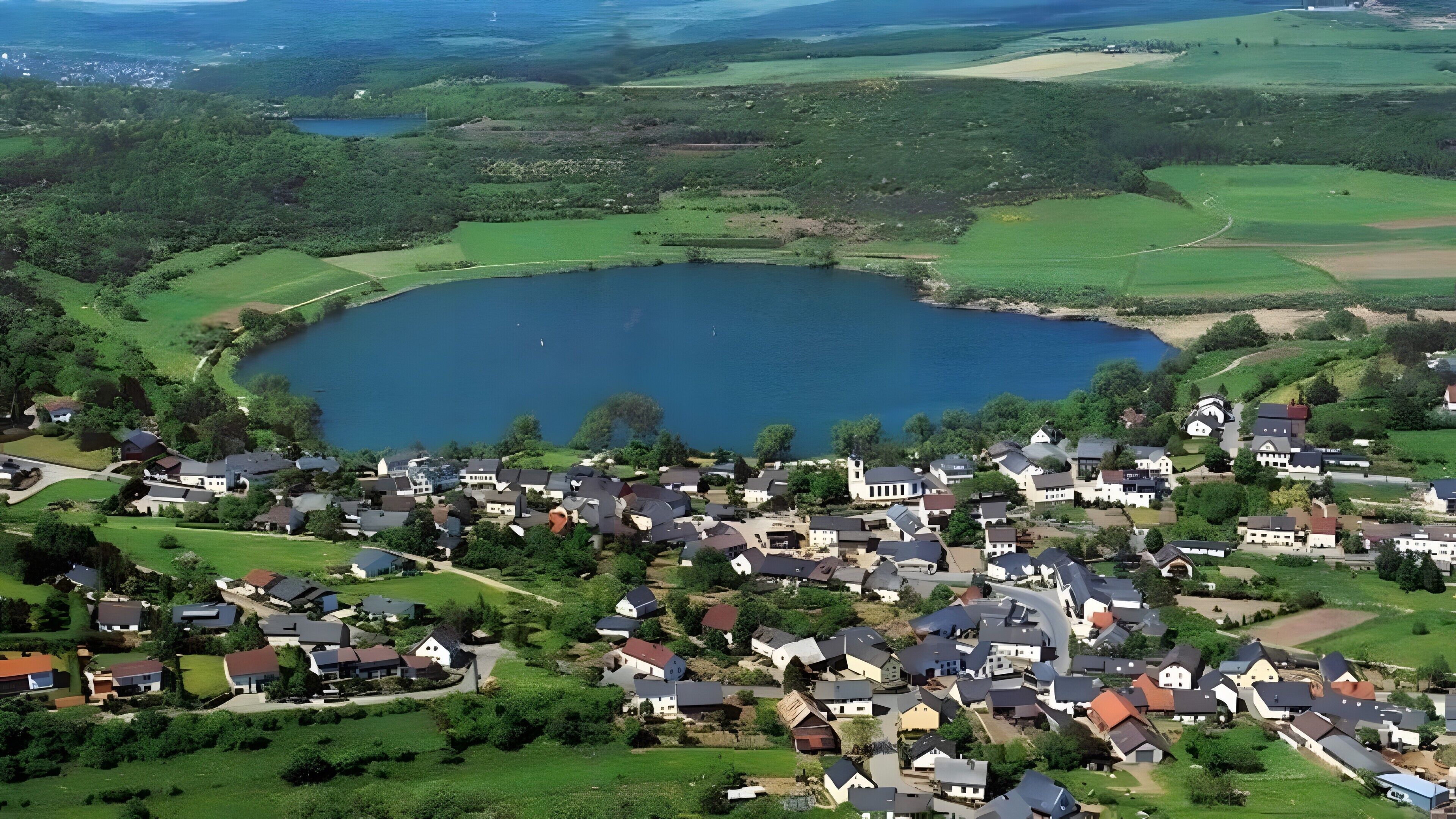 A lakeside residential area with houses, a large lake, and surrounding greenery.