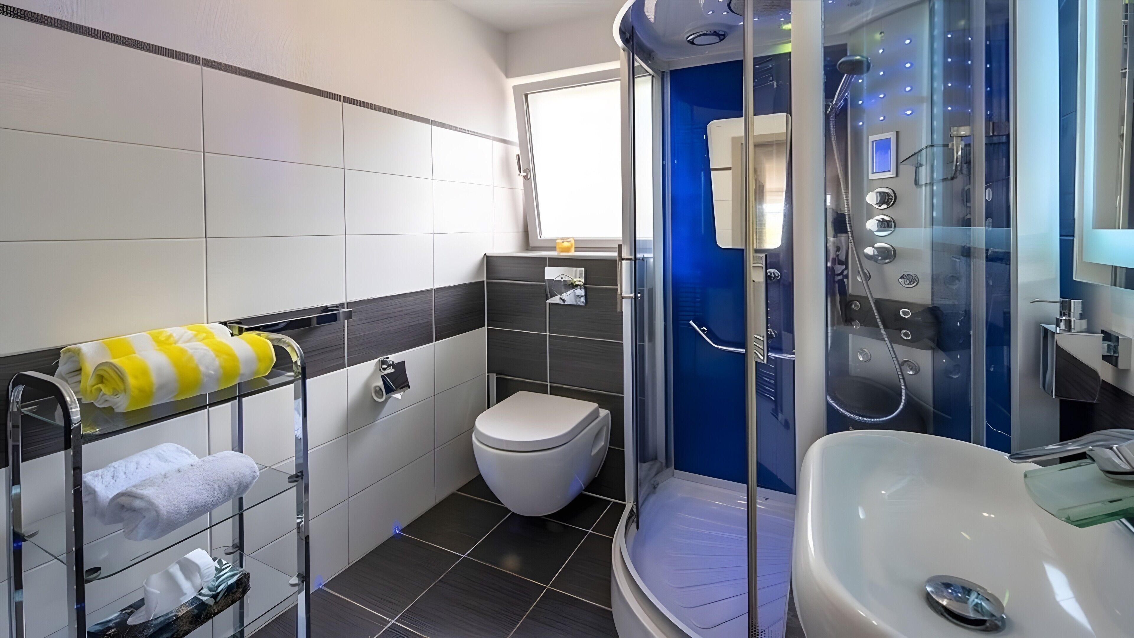 Ein modernes Badezimmer mit einer gläsernen Duschkabine, einer weißen Toilette und einem Waschbecken.