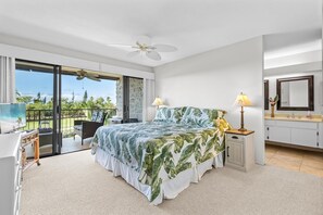Ein Schlafzimmer mit einem großen Bett, einem Balkon mit Aussicht, einem Deckenventilator und einem Badezimmer mit Spiegel.