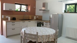 A compact kitchen with a dining table, built-in appliances, and a window with a view.