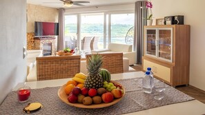 A dining area with a fruit bowl, a candle, and a water bottle on a patterned table.
