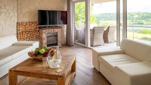 Un salon avec une cheminée, deux canapés, une table basse ornée de fleurs et un téléviseur.