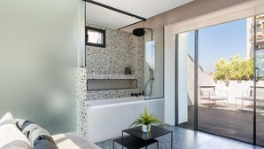 Un baño moderno con una bañera independiente, cabina de ducha de vidrio y una pequeña mesa con una planta.