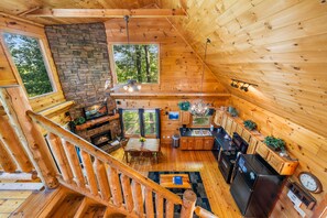 Eine Holzhütte mit rustikalem Interieur, einem Steinkamin, einem Essbereich und einer Küche.