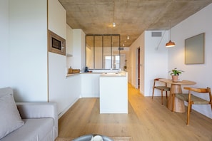 Una cocina moderna con una isla central, una mesa de comedor de madera con sillas y un sofá.