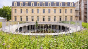 A historic building with a circular courtyard, a central fountain, and a surrounding garden.