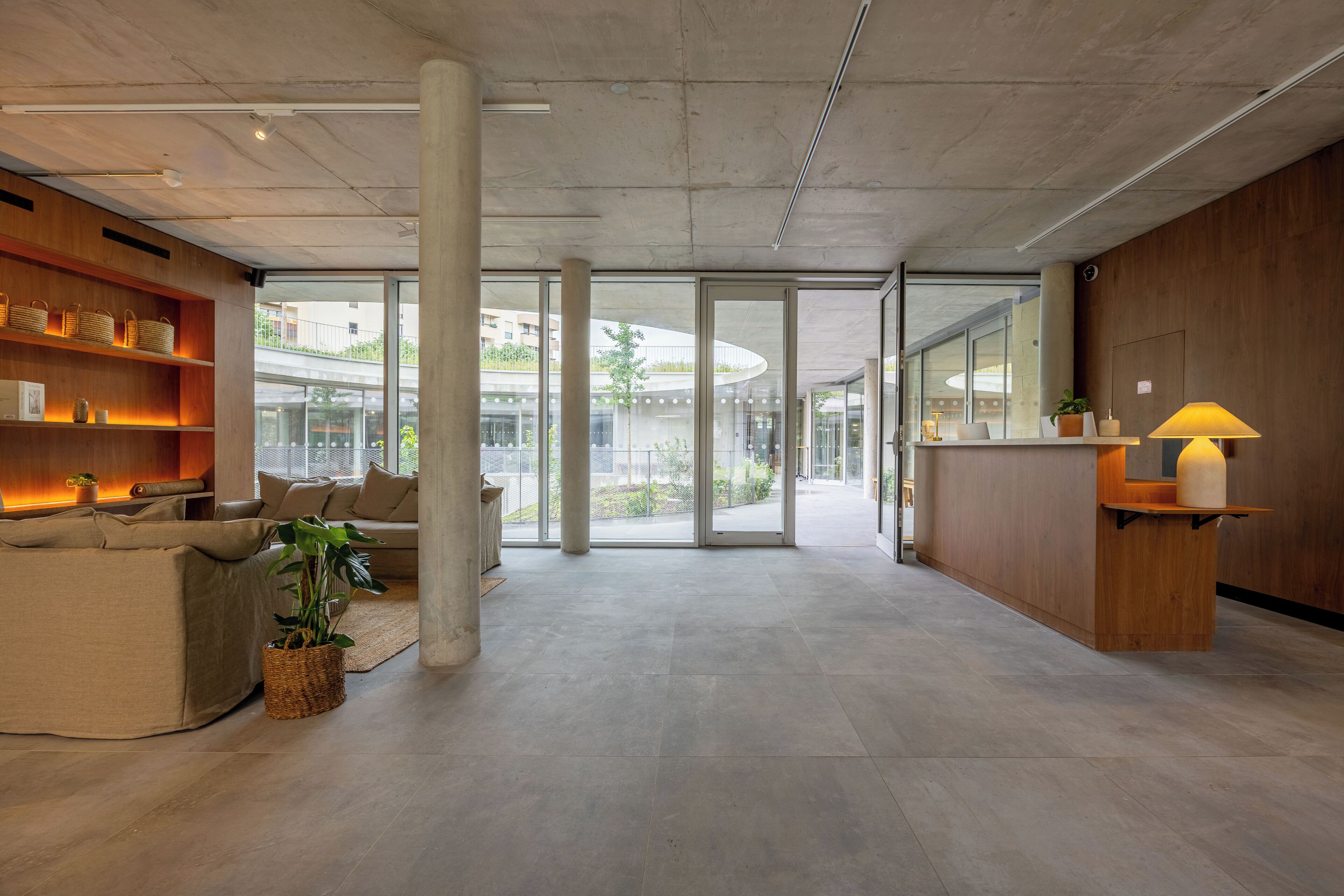 A modern lobby with a reception desk, seating area, and large windows.