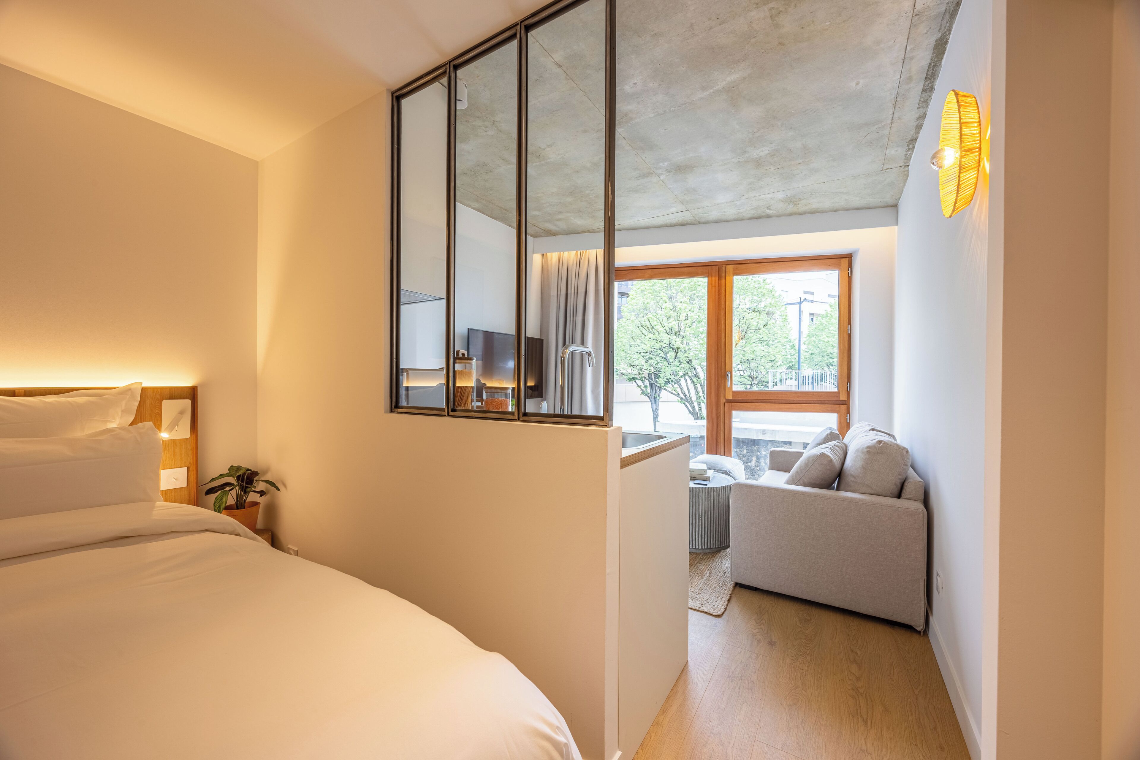 Ein Schlafzimmer mit Bett, großem Spiegel, Fernseher und Fenster mit Blick ins Freie.
