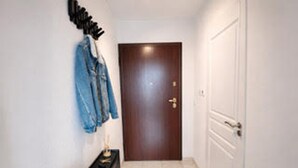 A hallway with a wooden door, a bench, and a plant on the left. - Charming apartment, lake view - 2 guests (Neuvecelle)