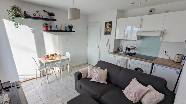 A compact living space with a sofa, a dining table, a kitchen area, and a washing machine. - Charming apartment, lake view - 2 guests (Neuvecelle)