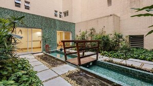 A courtyard with a swimming pool, tiled walls, and potted plants. - Beautiful beachfront apartment with unobstructed ocean views, pool, and sauna. (Bertioga)