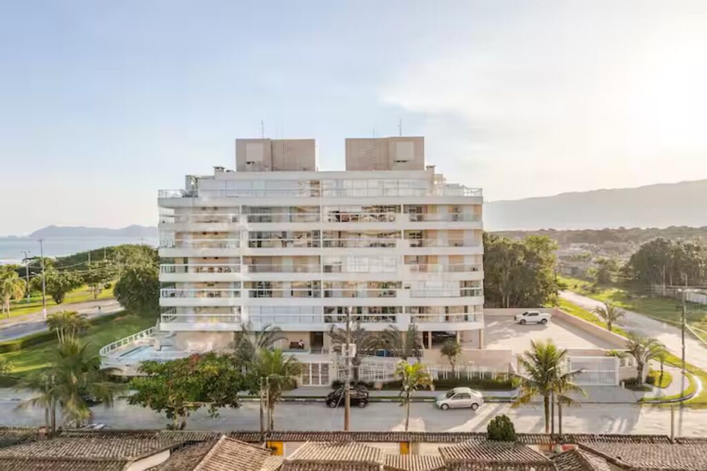 Un hôtel à plusieurs étages, doté de balcons, d’un parking et offrant une vue sur la mer.