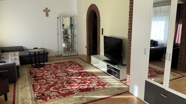 A living room with a sofa, TV, and a glass cabinet. - Vacation apartment/ accommodation for 5-6 persons in Bodenwerder (Bodenwerder)