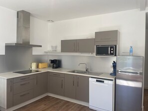 A modern kitchen with grey cabinets, a stainless steel range hood, a microwave, a dishwasher, and a water dispenser. - Charming house, pets welcome - 4 guests (Saint-Jean-de-Monts)