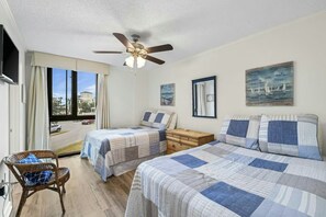 A bedroom with two beds, a ceiling fan, a window with a view, and a wooden nightstand. - ⭐Enclave 203B ☀Walk to the Beach ☀Community Pool~Tennis and Volleyball Courts⭐ (Destin)