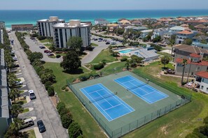 Ein Wohngebiet mit zwei Tennisplätzen, einem Parkplatz und Blick auf den Ozean.