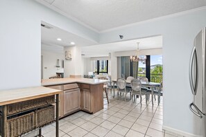 Una cocina moderna con una isla grande, comedor con sillas y vistas al exterior.