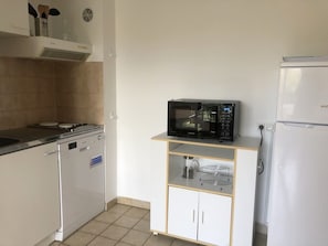Eine Küche mit einer Mikrowelle auf einem Regal, einem Herd, einem Geschirrspüler und einem Kühlschrank.