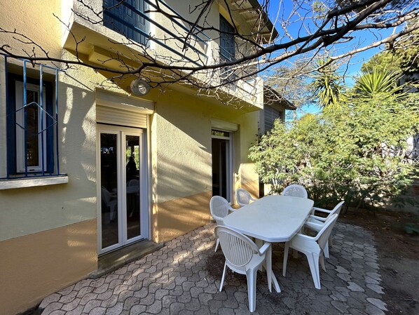 A patio with a table and chairs, a sliding glass door, and a small garden area. - Detached house, near the beach - 6 guests (Argelès-sur-Mer)