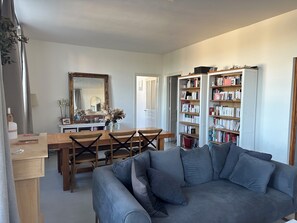 A living room with a sofa, a dining table with chairs, a bookshelf, and a mirror. - Maison Cœur de Famille - Between town and country (Chauvigny)
