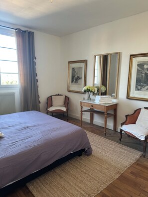 A bedroom with a bed, a chair, a table with a vase, and two framed pictures on the wall. - Maison Cœur de Famille - Between town and country (Chauvigny)