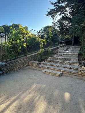 A gravel area with stone steps leading up to a garden area with climbing plants and trees. - Maison Cœur de Famille - Between town and country (Chauvigny)