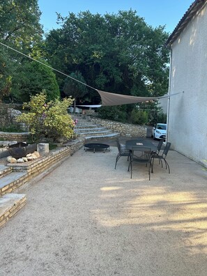 A patio with a table and chairs, a stone wall, and a car parked outside. - Maison Cœur de Famille - Between town and country (Chauvigny)